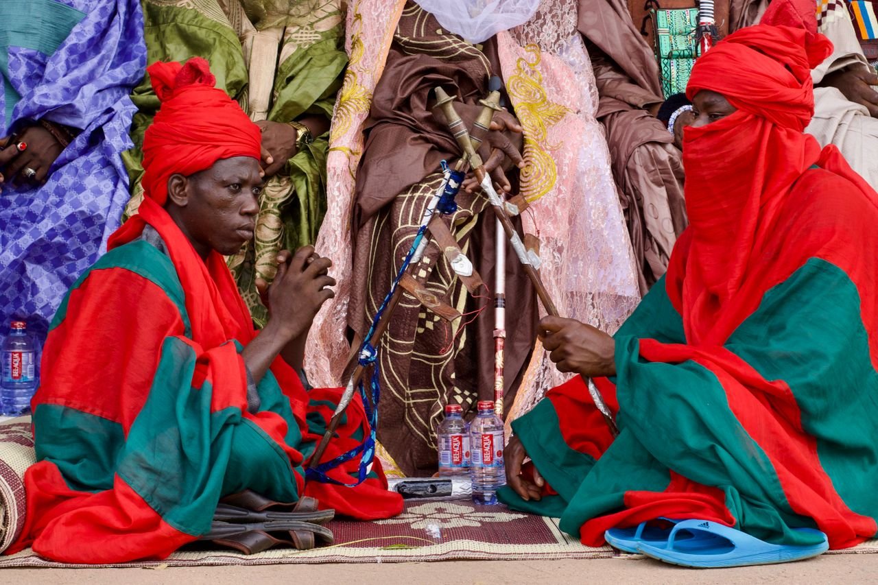 Two men in vibrant traditional clothing participate in a cultural ceremony.