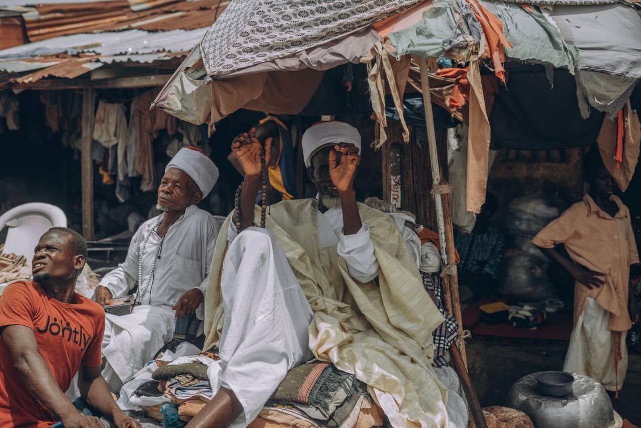 About Candid street photography capturing a vibrant market scene with people in traditional attire under makeshift stalls.